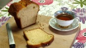 Houten broodplank met aangesneden citroencake en een kopje thee